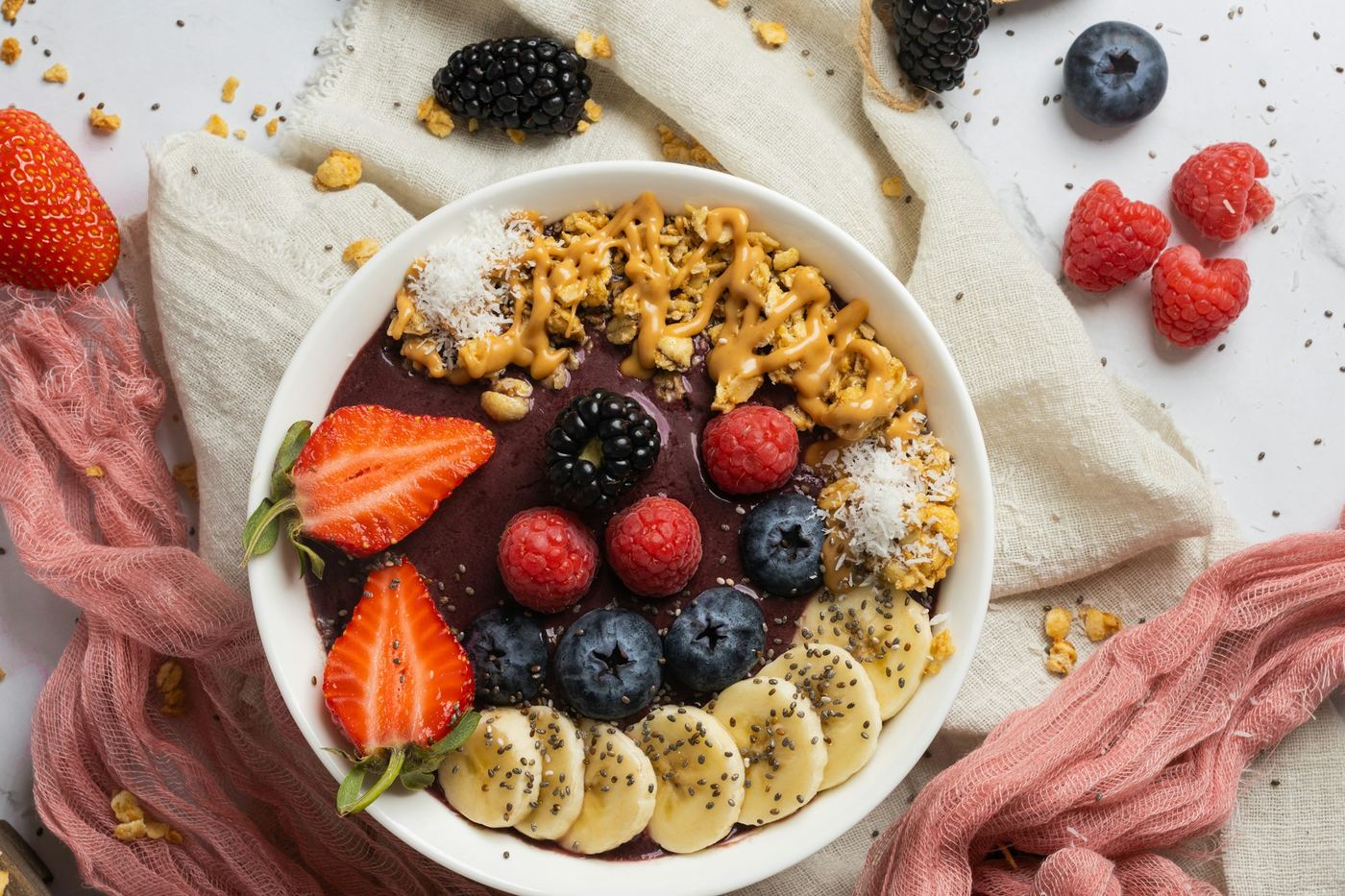Açaí Bowl mit Beeren, Banane und Granola auf warmem Stoff — Açaí als Winter-Frühstück